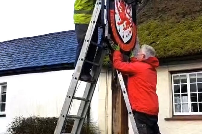 The Drewe Arms sign being raised and put back into pride of place.
