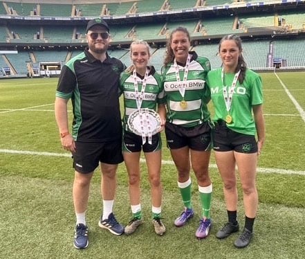 Okehampton's female rugby players and their coach with their medals at Twickenham.