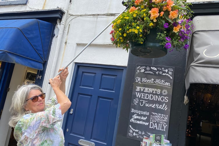 Linda Walker, of 'A Scent-Station' florists, in Tavistock, is urging fellow Tavistock traders to keep watering the hanging baskets decorating the high street in the summer heat.