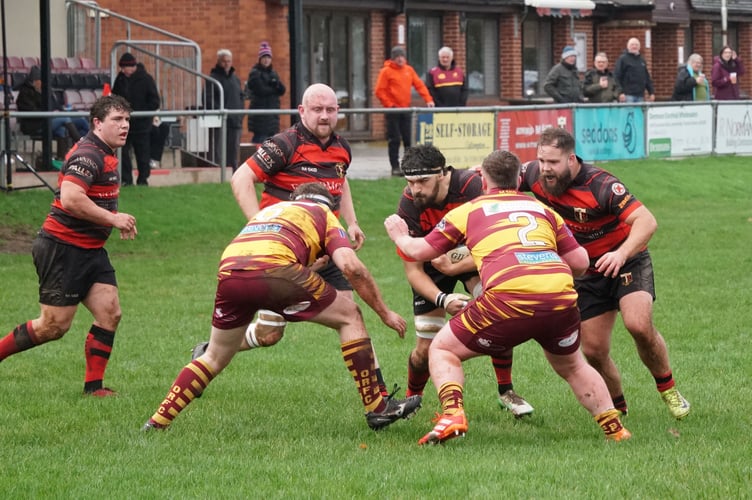 Okehampton forwards Alex Cross, left, and Jack Rutley, right, team up to halt Cullompton ball carrier Sam Cooke. Picture: Reith May.