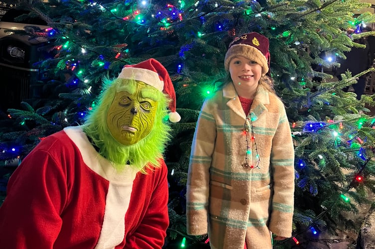 The Grinch and a youngster in front of the lit tree in North Tawton Square.