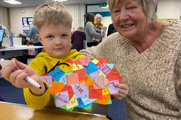 Lawson Collings-Barnes and his grandma Marjorie decorating a reading tree sculpture in Tavistock Library.