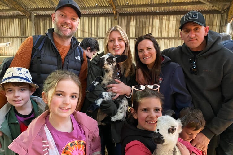 Two families embrace a pair of lambs at Greenwell Farm, Meavy.