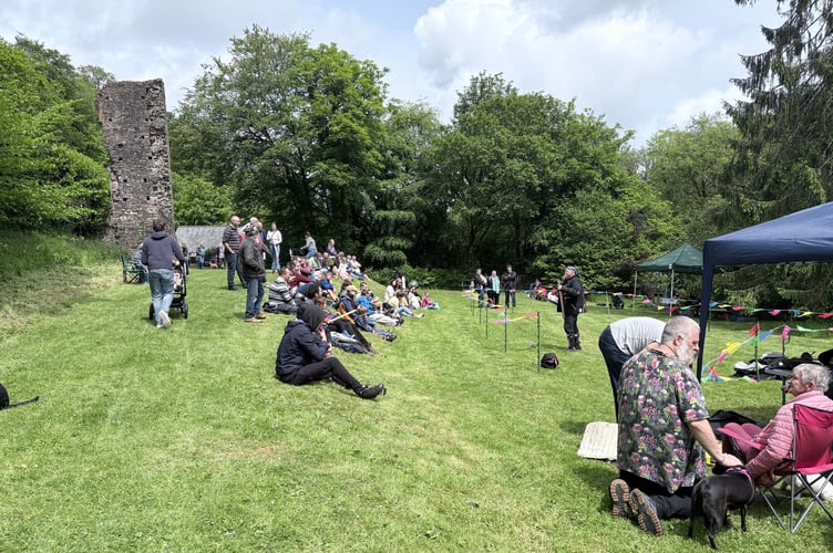 Visitors enjoying a break in the weather and relaxing next to the castle ruins.