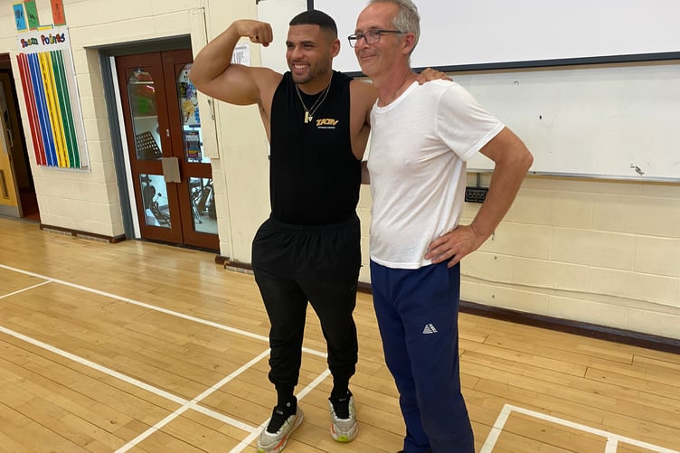 TV Gladiator Steel motivates sporting Horrabridge School youngsters and compares biceps with headteacher John Clarke.