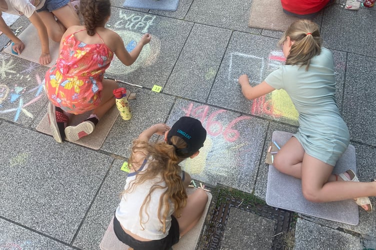 Young artists decorating Tavistock high street for the Lions Carnival Week pavement art competition.