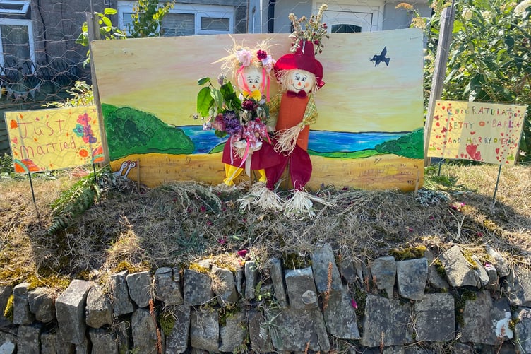 A mini-couple of scarecrows are wedded on a garden wall in Bere Alston for the judging of the Bere Alston In Bloom competition.