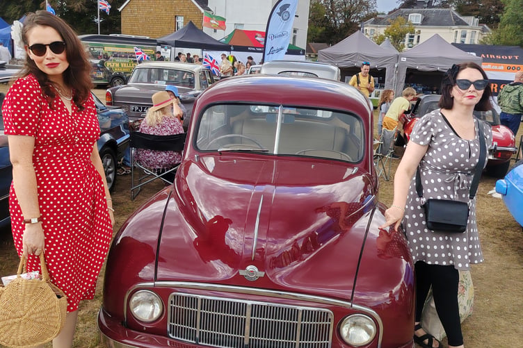 Two stylish visitors to RAF Harrowbeer's 1940s Weekend admire a classic car on display.