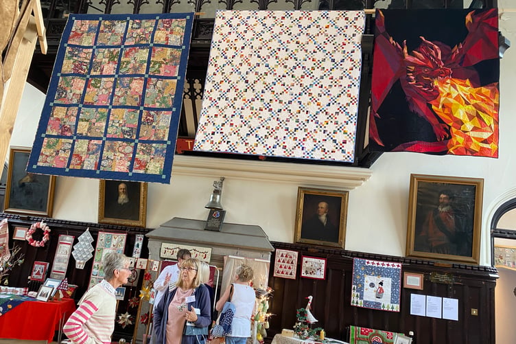 The colourful creations of the Goosey Quilters group hang high at the community needleworkers' exhibition in Tavistock Town Hall.